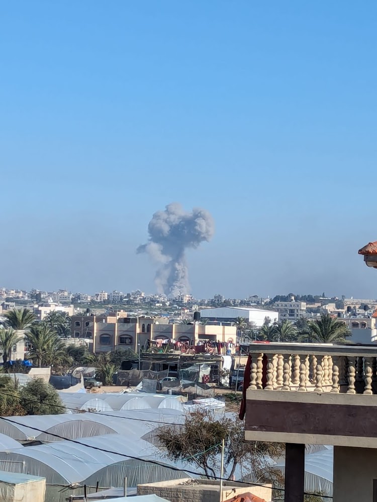 Bomb Explosion in Gaza Buildings in Gaza City with smoke from an exploding bomb visible in the distance