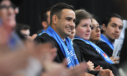 A photo of Students on stage during convocation laughing and clapping