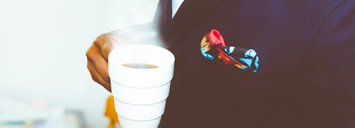 sharply dressed person holding a cup of coffee