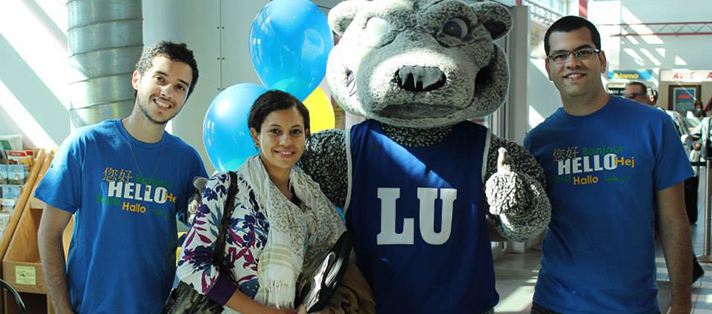 A studnet arriving at the Thunder Bay Airport and being greeted by Lakehead staff and students with wolfie