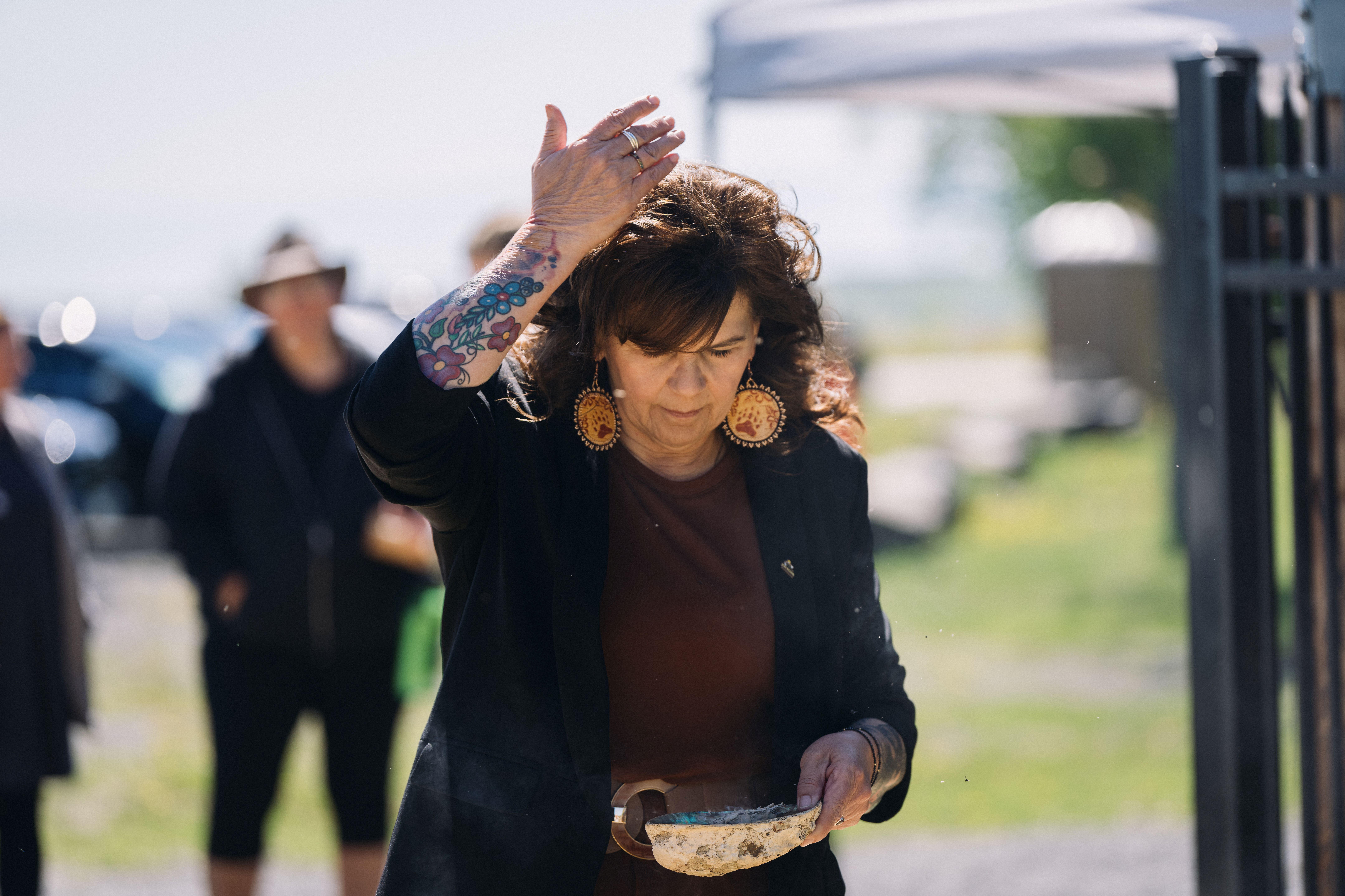 Chief Michele Solomon Participating in a Smudging Ceremony Chief Michele Solomon wafts smoke over her head with her hand during a smudging ceremony