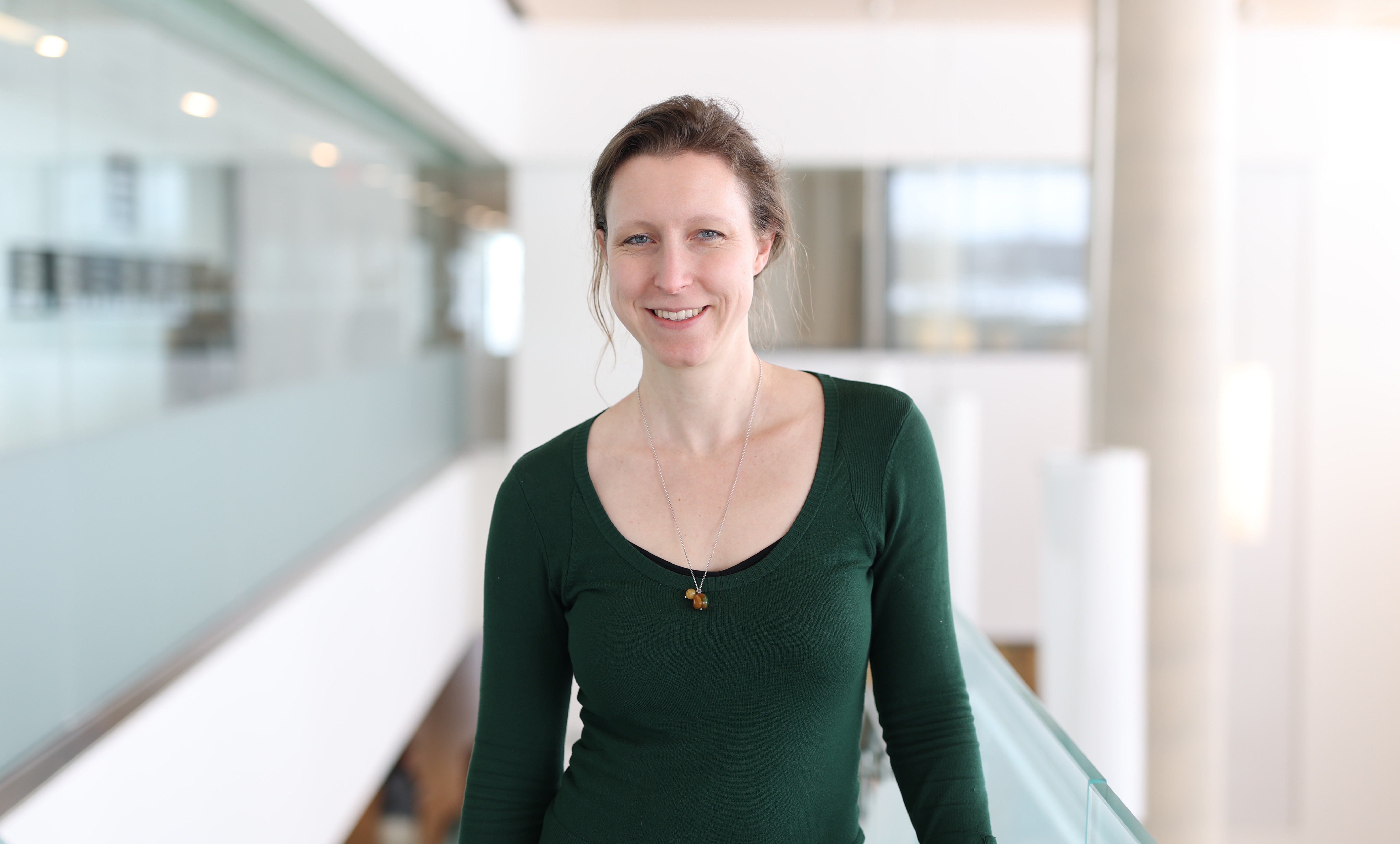 Dr. Kathryn Walton Dr. Kathryn Walton, wearing a green sweater and a pendant necklace, stands at the top of the staircase in Simcoe Hall