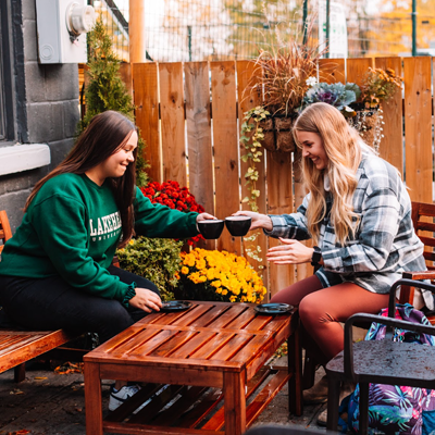 Two students sitting outside in a beautiful yard