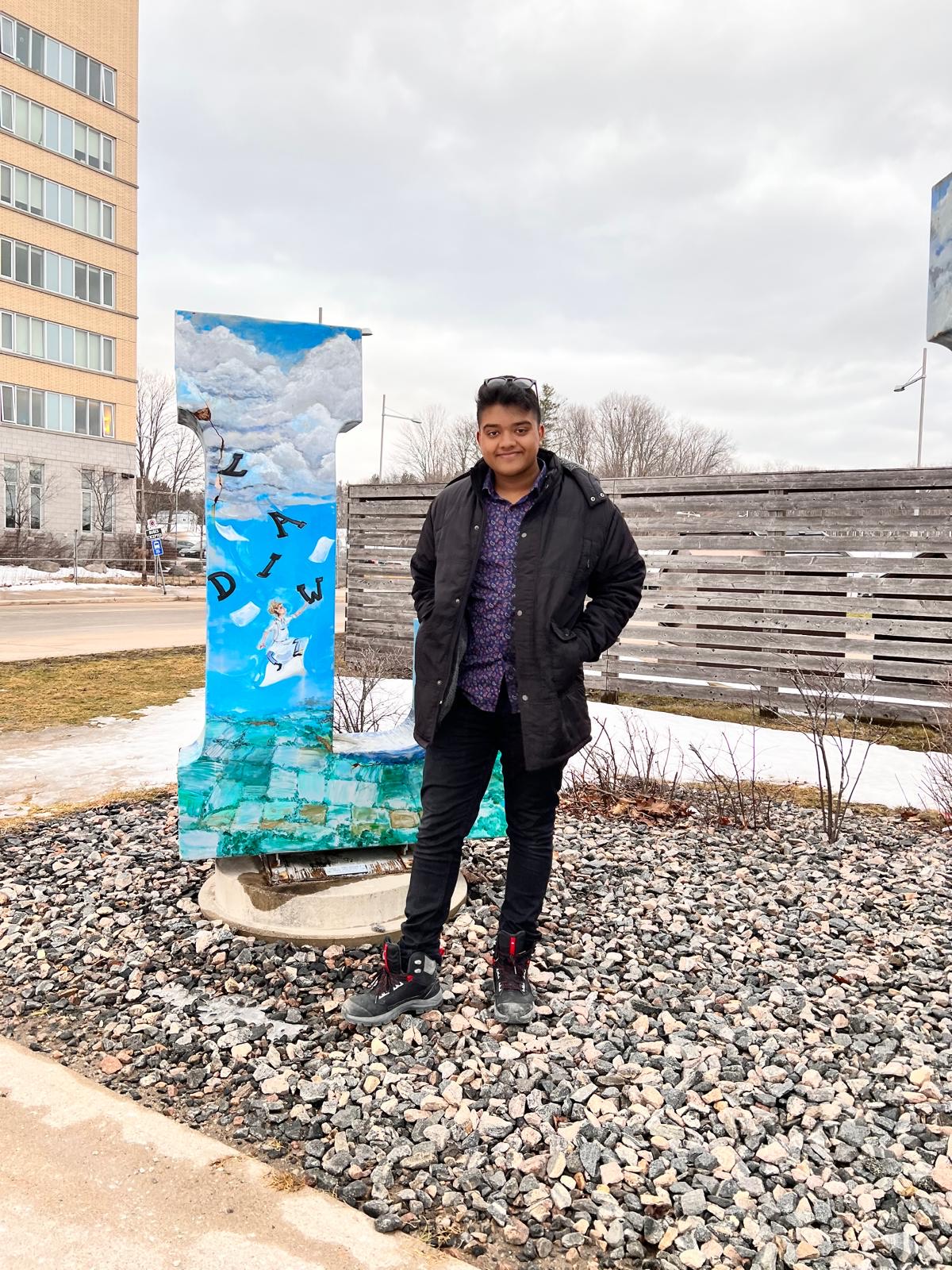 Student Joel Abraham on the Orillia Campus Joel Abraham stands outdoors beside a sculpture on the Lakehead Orillia campus