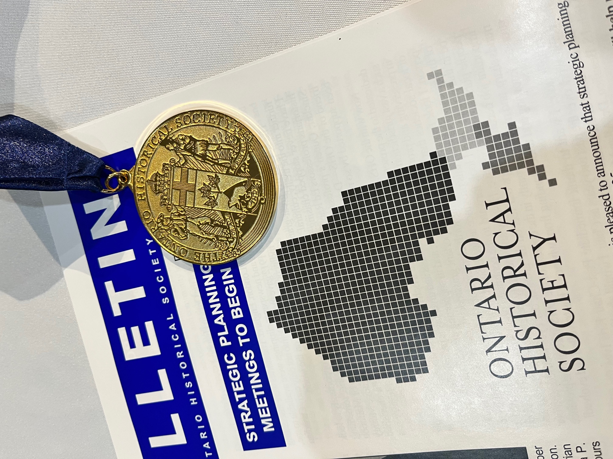 Ontario Historical Society Cruikshank Gold Medal Ontario Historical Society Cruikshank Gold Medal placed on top of an Ontario Historical Society Bulletin