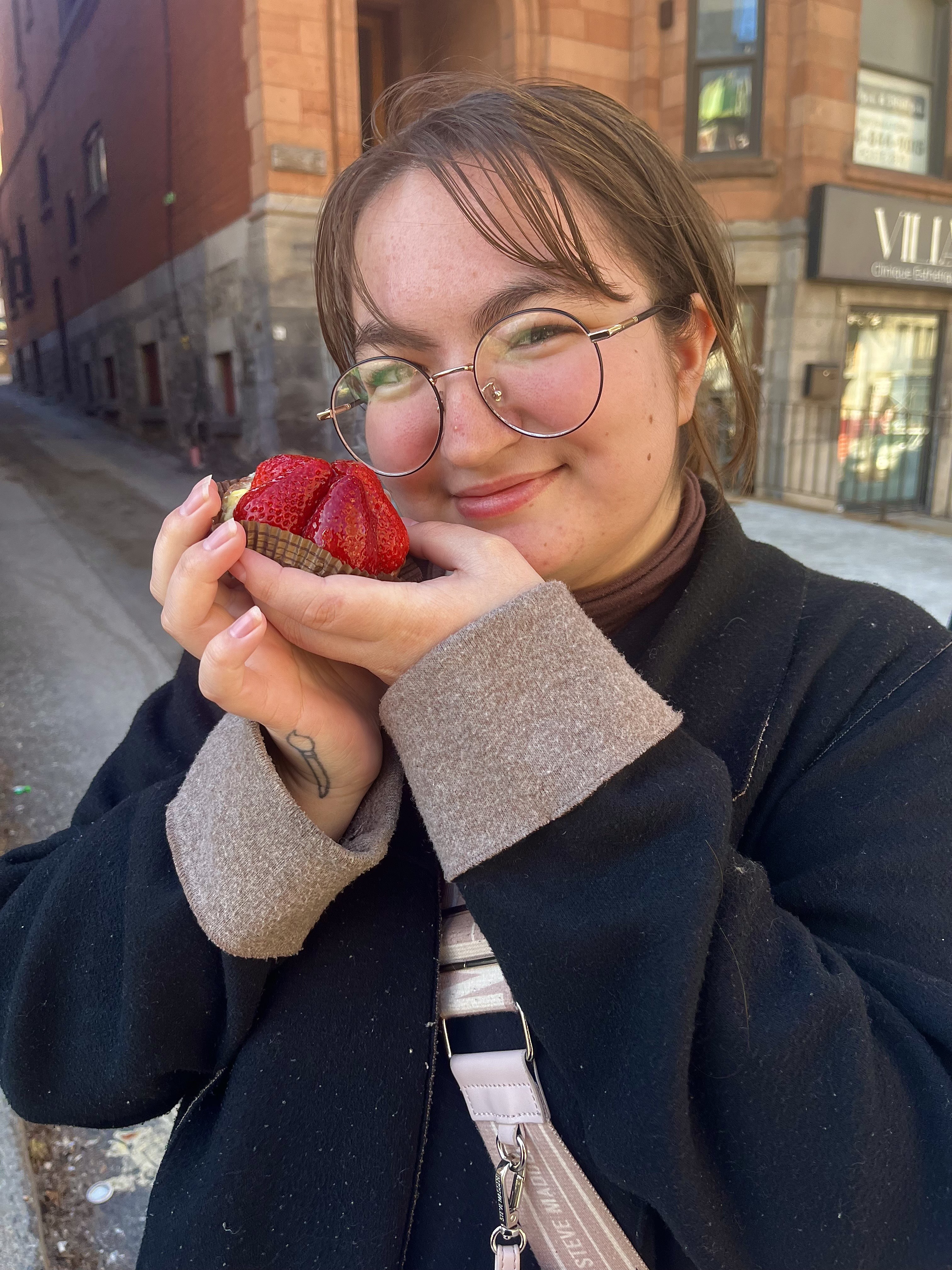 Tashie Broadbent Tashie Broadbent holds a strawberry tart in front of a building
