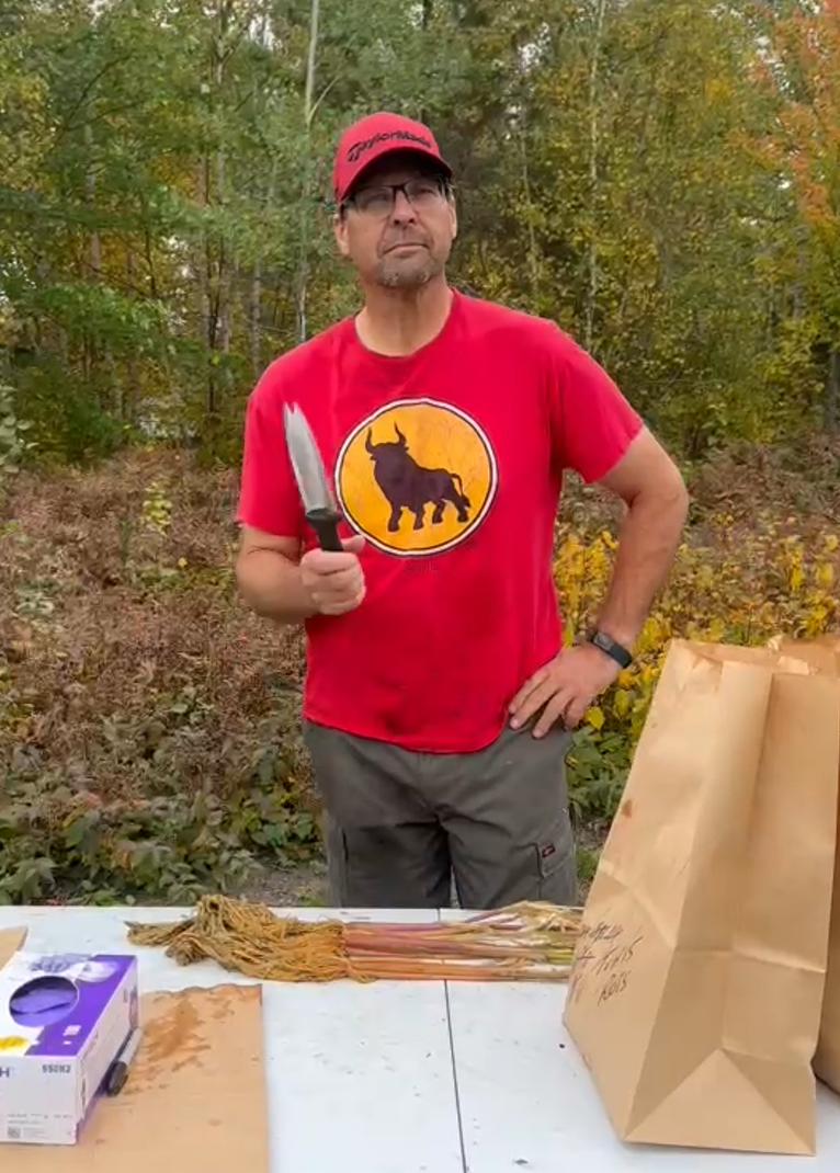 Dr. Vincent Palace Processing Wild Rice Dr. Vincent Palace at a table outdoors holding an implement for processing wild rice