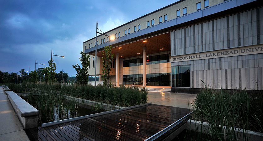 The front facade of the Orillia Campus academic building at dusk with focus on the name Simcoe Hall