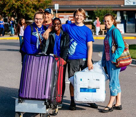 Students outside a residence hall smiling